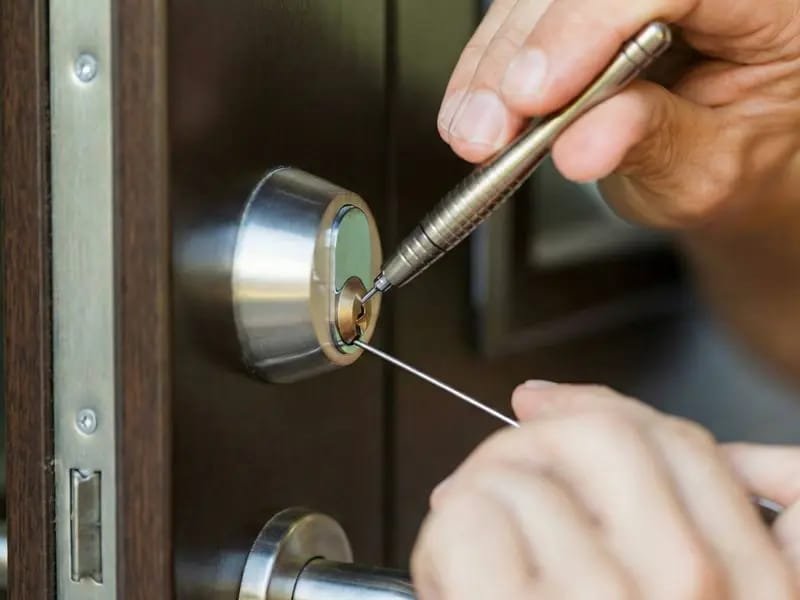 Chaveiro trabalhando no cilindro da fechadura de uma porta de madeira